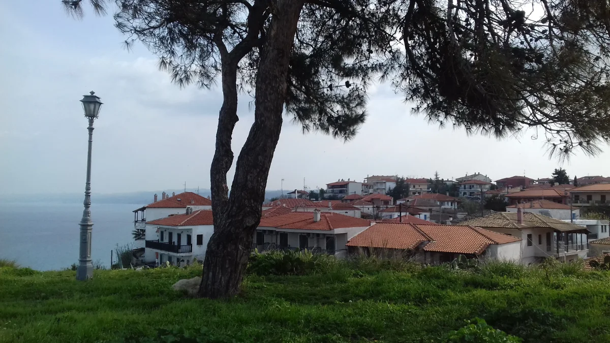 Cobblestone street in Afitos village with traditional stone houses and sea view in the distance
